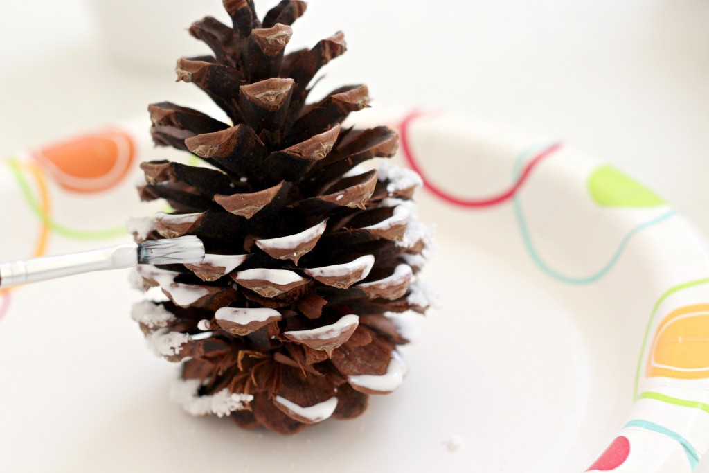 snowy-pine-cone-applying-glue